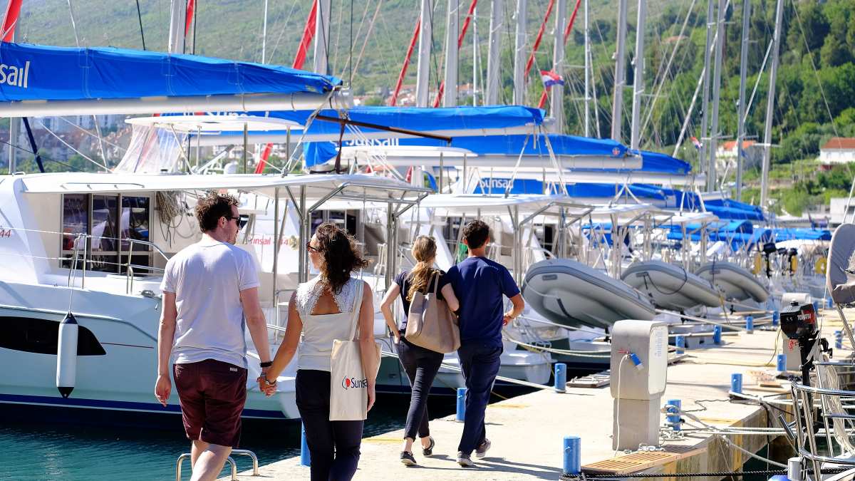 Couples walking along a jetty next to yachts