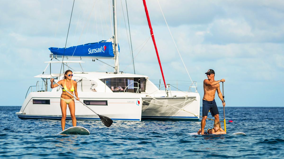 Gelukkig gezin paddleboarden met uitzicht op het jacht