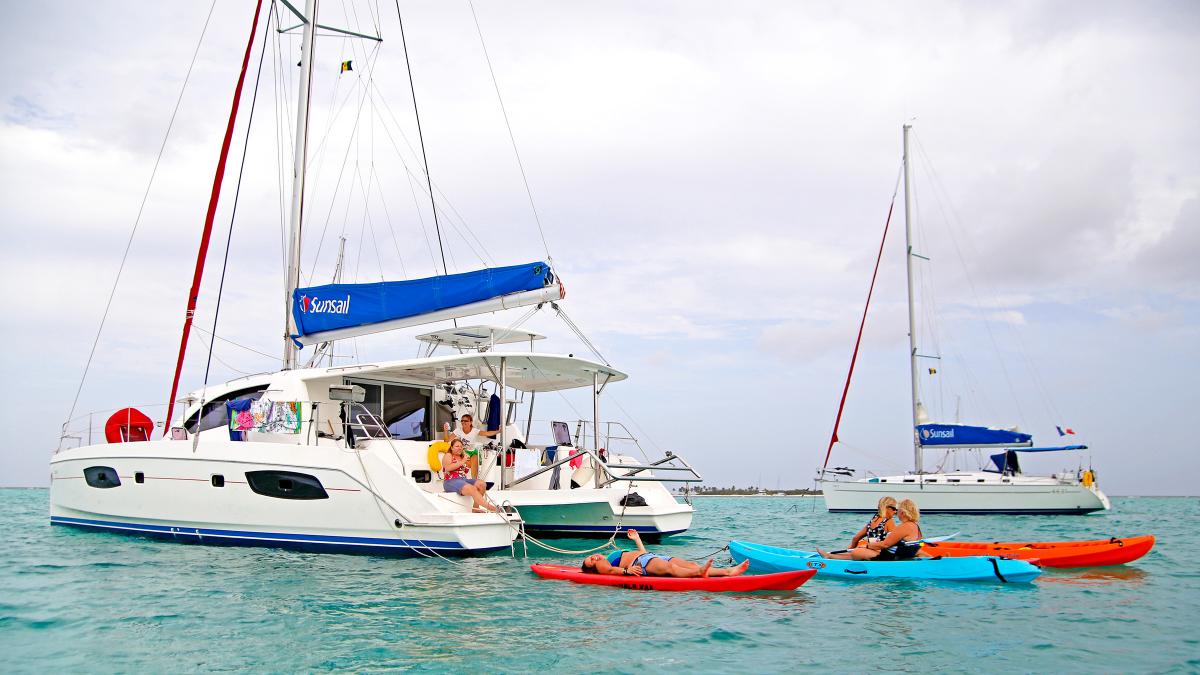 Guests enjoying kayaks on the sea in front of yachts